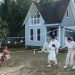 Happy family playing tug of war in front of cozy houses during a summer day.